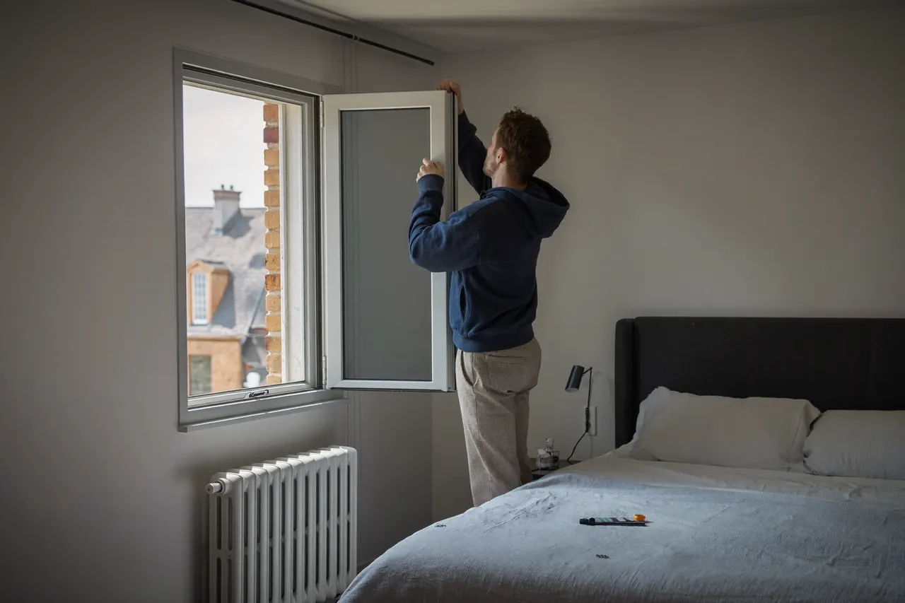An installer fitting a new bedroom window from inside the room